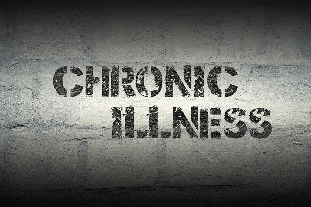 The words Chronic Illness stamped in black on a grey brick wall. 